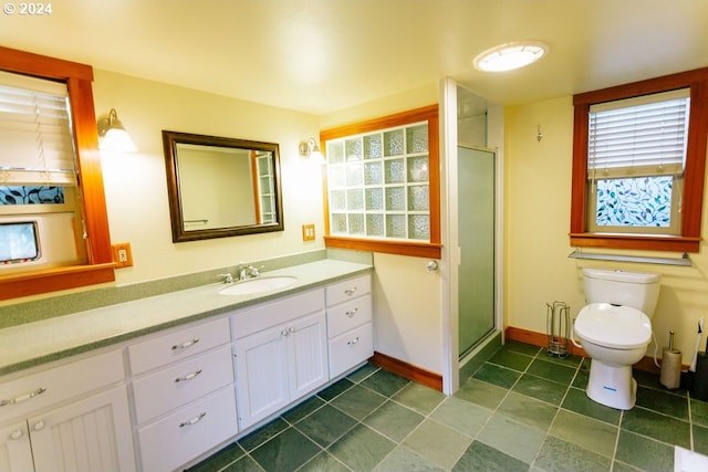 full bathroom featuring toilet, vanity, baseboards, a stall shower, and plenty of natural light