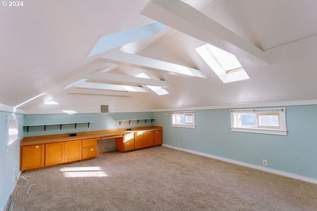 unfurnished office featuring visible vents, light colored carpet, lofted ceiling with beams, and baseboards