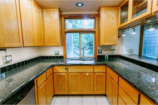 kitchen with dishwasher, sink, dark stone countertops, and light tile patterned floors