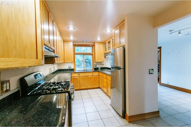 kitchen featuring sink, dark stone countertops, and stainless steel fridge