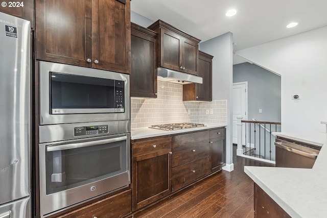 kitchen featuring dark brown cabinetry, stainless steel appliances, backsplash, and dark hardwood / wood-style flooring