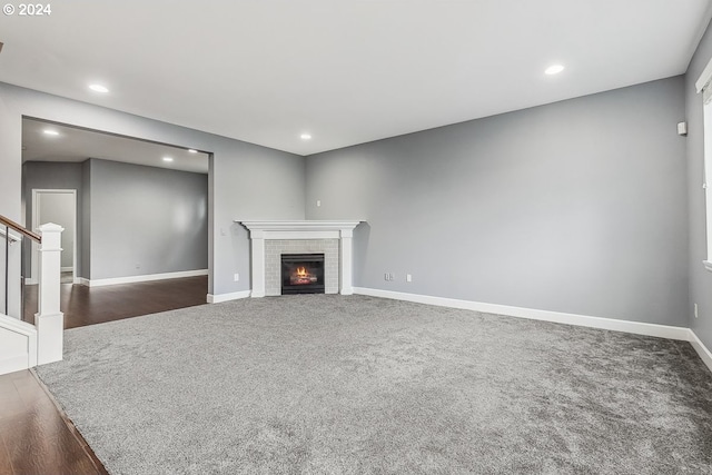 unfurnished living room with a brick fireplace and dark hardwood / wood-style flooring