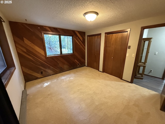 2822 S Tenmile Lk, Lakeside, OR 97449 - unfurnished bedroom with a textured ceiling, carpet flooring, multiple closets, and wood walls
