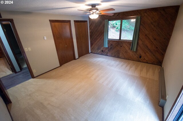 unfurnished bedroom featuring wood walls, ceiling fan, and carpet floors