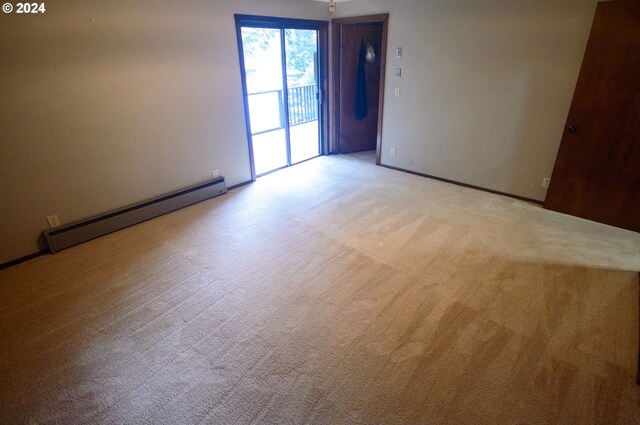 carpeted empty room with a baseboard heating unit