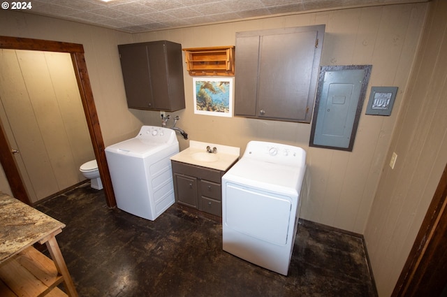 laundry room featuring washer and clothes dryer, wood walls, electric panel, laundry area, and a sink