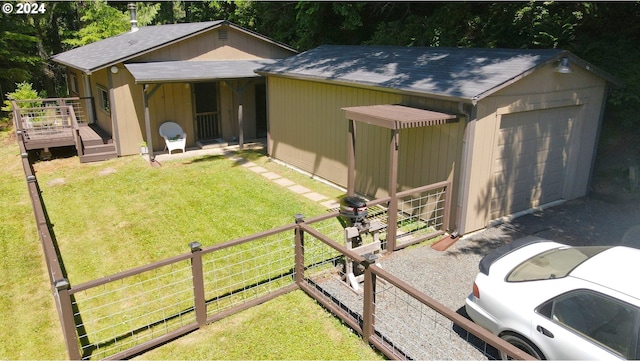 view of front of home featuring a shingled roof, fence, a wooden deck, a front yard, and an outbuilding