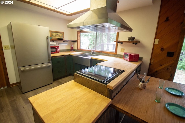 kitchen with open shelves, freestanding refrigerator, a sink, light wood-style floors, and exhaust hood