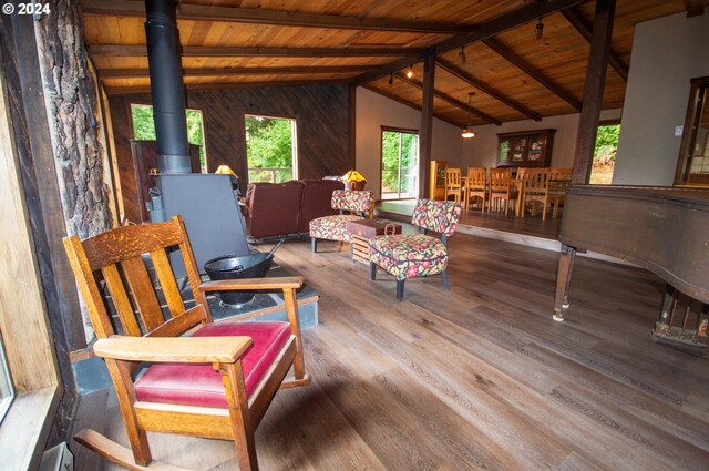 living room with lofted ceiling with beams, wood ceiling, hardwood / wood-style flooring, and a wood stove