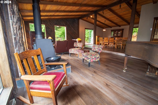 interior space with vaulted ceiling with beams, wood walls, wood ceiling, a wood stove, and wood finished floors