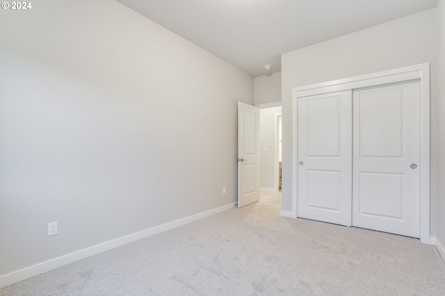 unfurnished bedroom featuring light colored carpet and a closet