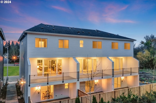 back house at dusk featuring a balcony