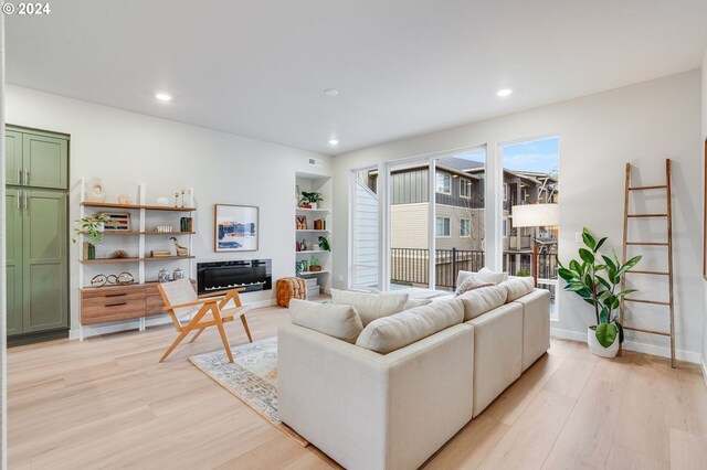 living room with built in shelves and light wood-type flooring