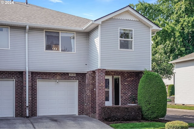 view of front of property featuring brick siding, roof with shingles, concrete driveway, and an attached garage