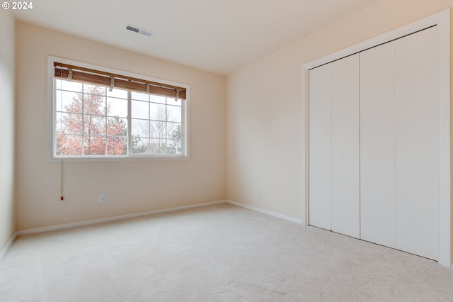 unfurnished bedroom featuring light carpet and a closet