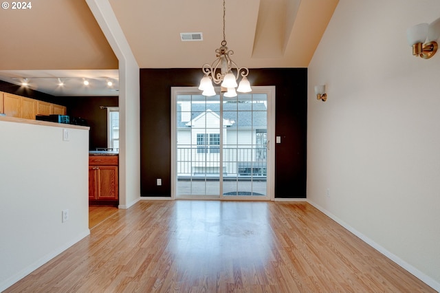 unfurnished dining area with light hardwood / wood-style flooring and a notable chandelier