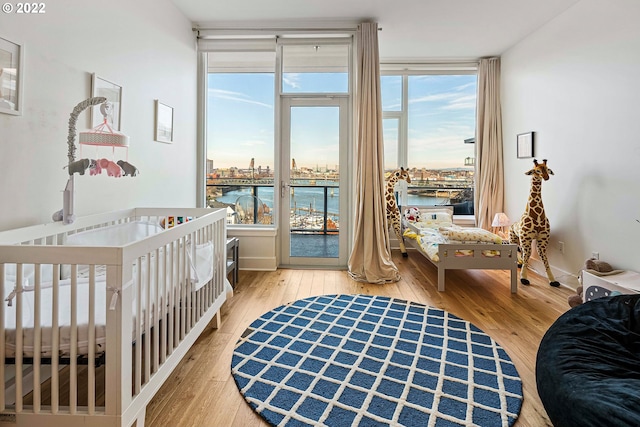 bedroom with a water view, a crib, and light hardwood / wood-style floors