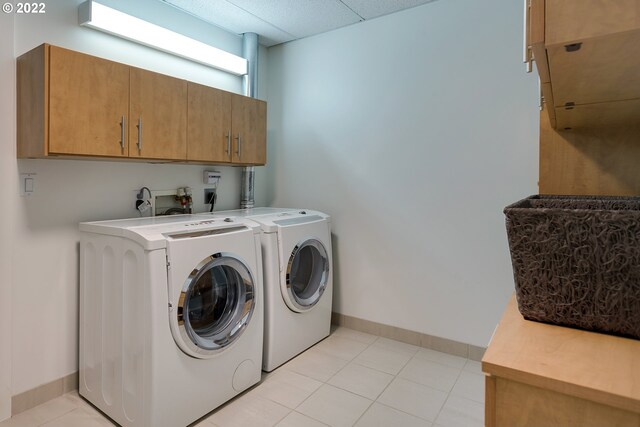 clothes washing area with cabinets, light tile patterned flooring, and independent washer and dryer