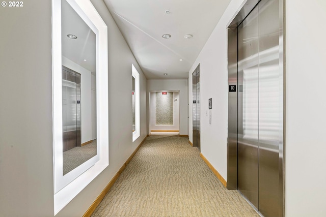 hallway with light carpet and elevator