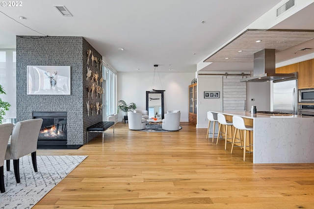 living room with a barn door, light wood-type flooring, and a large fireplace