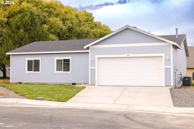 ranch-style home featuring a garage, a front lawn, and central AC unit