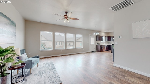 living area with ceiling fan with notable chandelier and light hardwood / wood-style floors