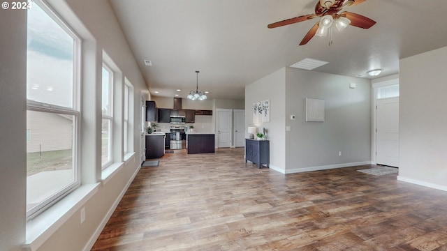 unfurnished living room with wood-type flooring and ceiling fan with notable chandelier