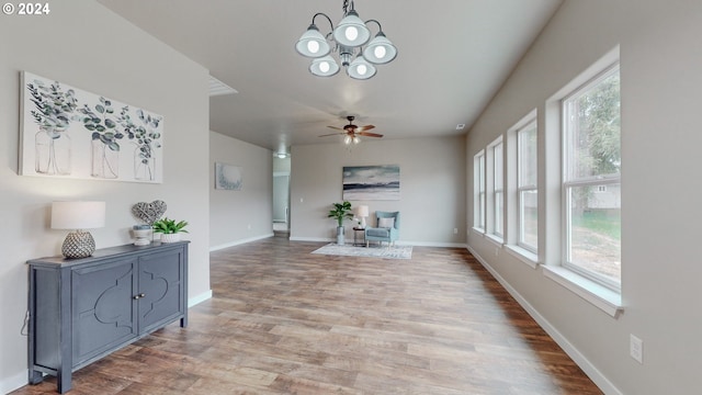 interior space featuring ceiling fan with notable chandelier, a healthy amount of sunlight, and wood-type flooring