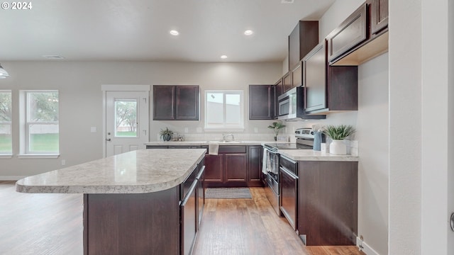 kitchen with light hardwood / wood-style flooring, dark brown cabinets, sink, stainless steel appliances, and a center island