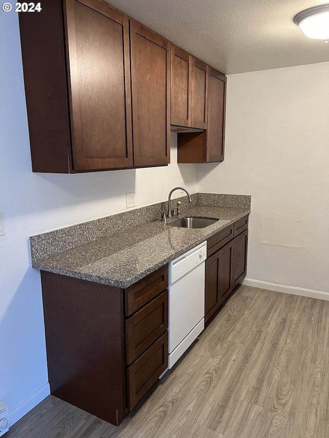 kitchen with white dishwasher, dark stone countertops, a textured ceiling, light hardwood / wood-style floors, and dark brown cabinetry