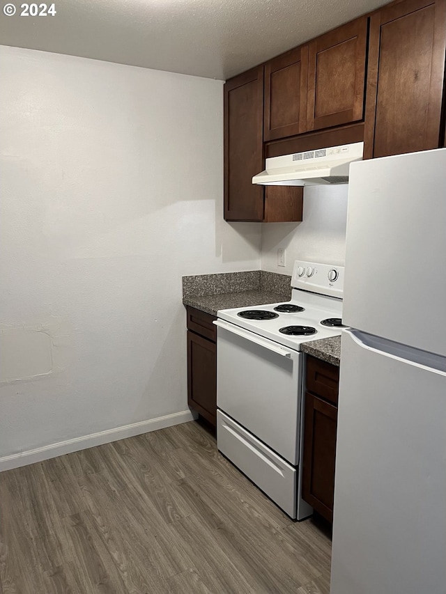 kitchen with light wood-type flooring, a textured ceiling, white appliances, and dark brown cabinetry