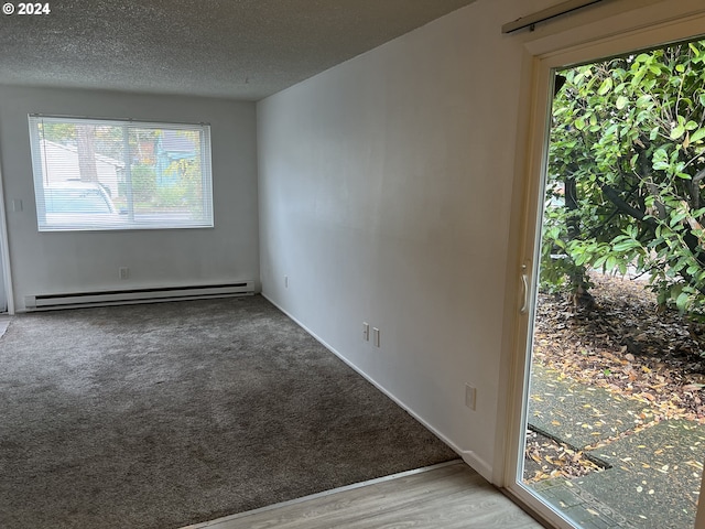 spare room featuring baseboard heating, a textured ceiling, and hardwood / wood-style flooring