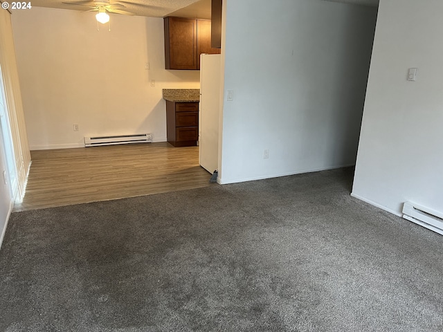 unfurnished living room with baseboard heating, ceiling fan, and dark wood-type flooring