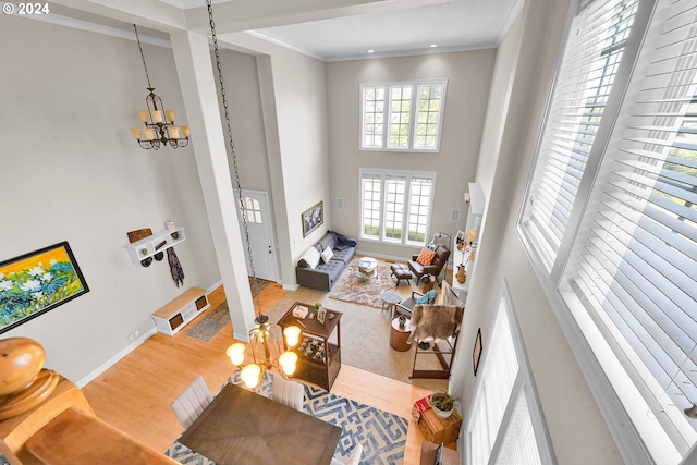 living room featuring crown molding, hardwood / wood-style floors, an inviting chandelier, and a high ceiling