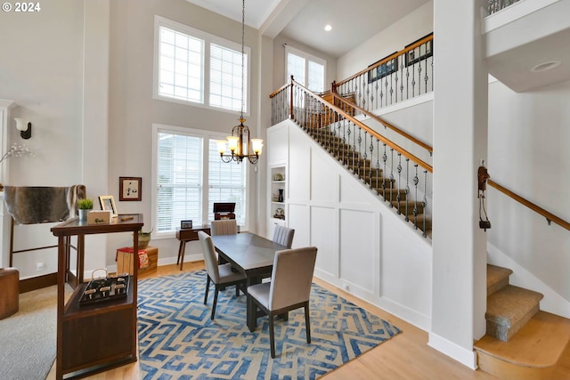 dining area with a high ceiling, wood-type flooring, and a notable chandelier