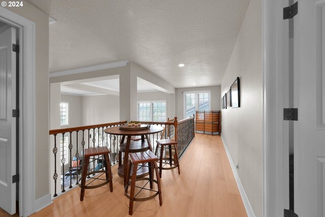 corridor featuring a textured ceiling, beam ceiling, and light hardwood / wood-style floors