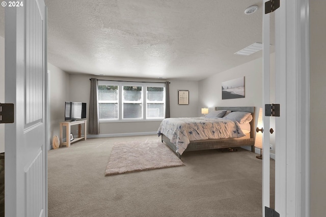 bedroom with a textured ceiling and light colored carpet