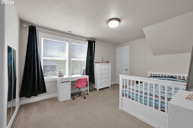 bedroom with a textured ceiling and light carpet