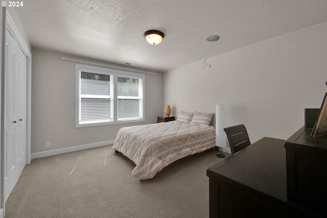 carpeted bedroom with a textured ceiling and a closet