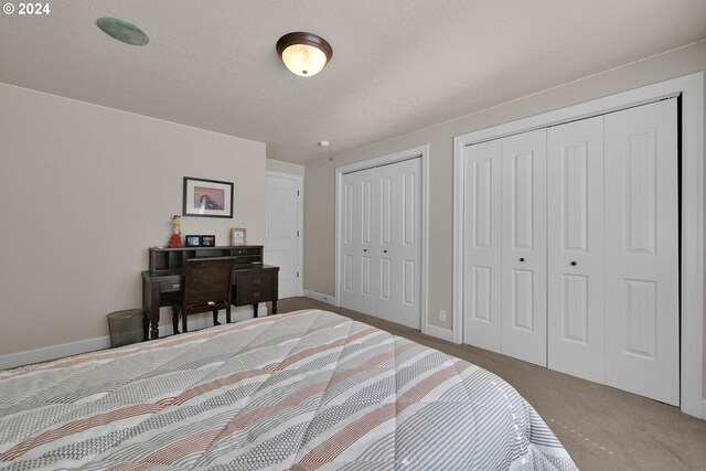 carpeted bedroom featuring multiple closets and a textured ceiling