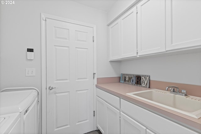 clothes washing area featuring independent washer and dryer, cabinets, and sink