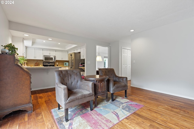 living room with a tray ceiling and light hardwood / wood-style flooring