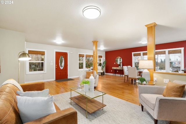 living room with light hardwood / wood-style floors, ornate columns, and a healthy amount of sunlight