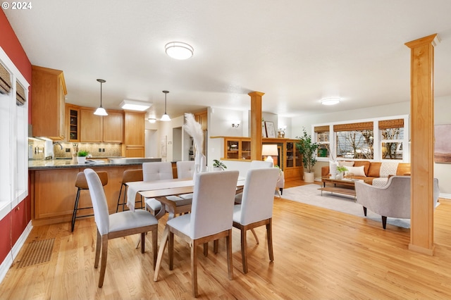 dining space featuring decorative columns and light hardwood / wood-style floors