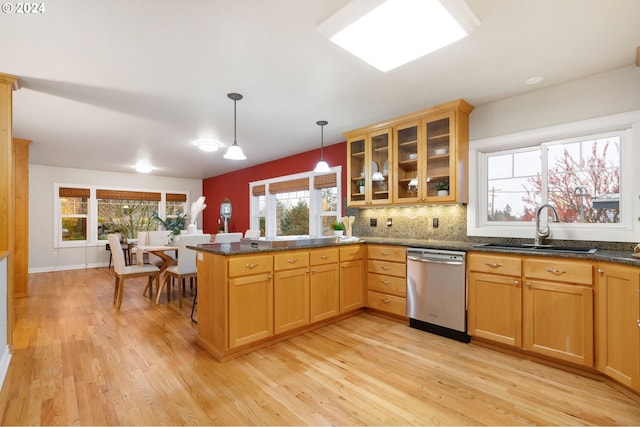 kitchen with sink, stainless steel dishwasher, light wood-type flooring, decorative light fixtures, and kitchen peninsula