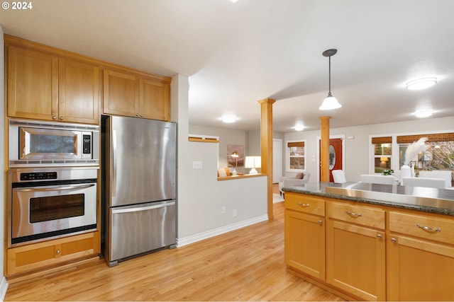 kitchen with appliances with stainless steel finishes, decorative columns, decorative light fixtures, and light hardwood / wood-style floors