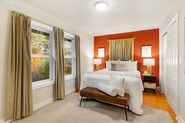 bedroom featuring a closet, light hardwood / wood-style flooring, and a textured ceiling