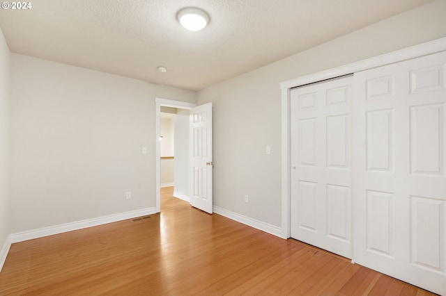 unfurnished bedroom featuring hardwood / wood-style floors, a textured ceiling, and a closet