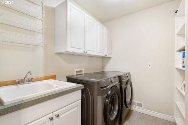 laundry area featuring separate washer and dryer, sink, and cabinets