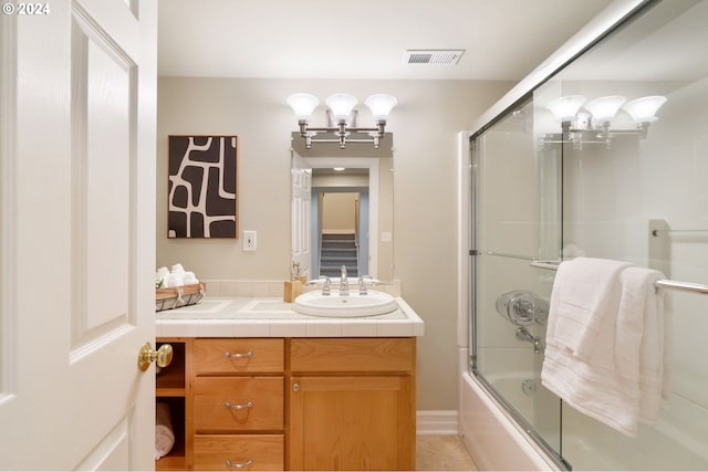 bathroom featuring tile patterned flooring, vanity, and enclosed tub / shower combo